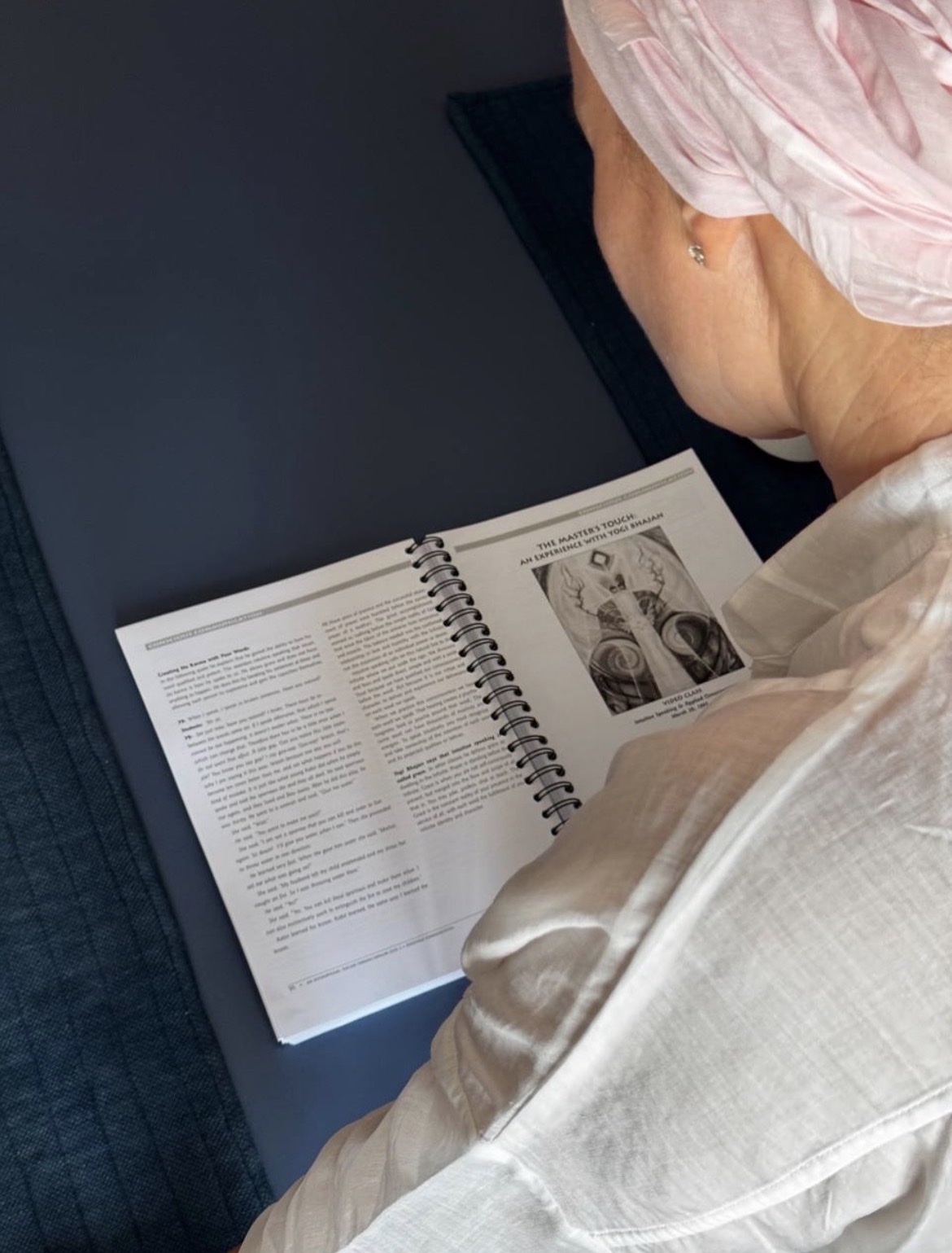 A student reading a spiral-bound practice workbook on a studio mat
